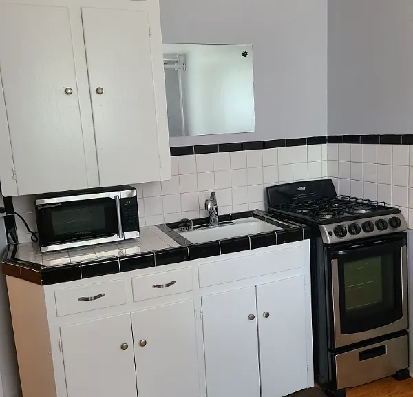 Kitchen with stainless steel gas range, stainless steel microwave, sink and disposal.