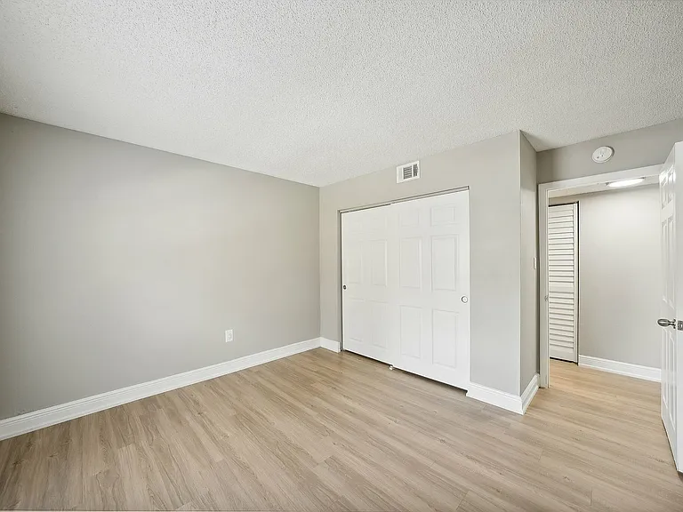 Bright and airy bedroom with light wood flooring and a spacious closet, offering a serene space for relaxation.