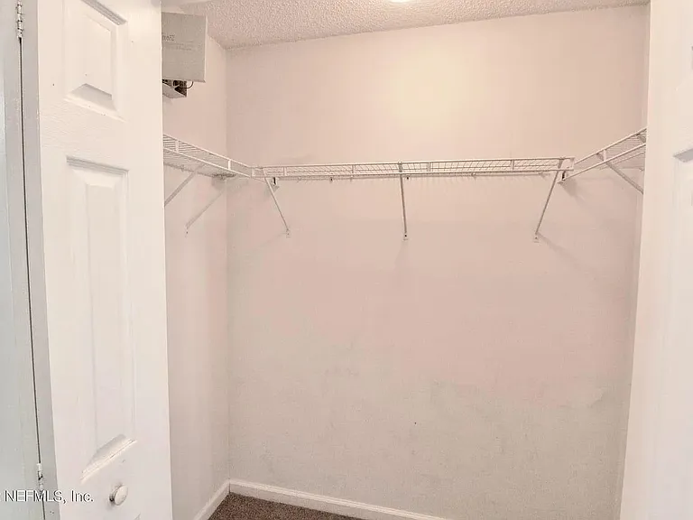 Walk-in closet with wraparound wire shelving and ample hanging space for organized storage.