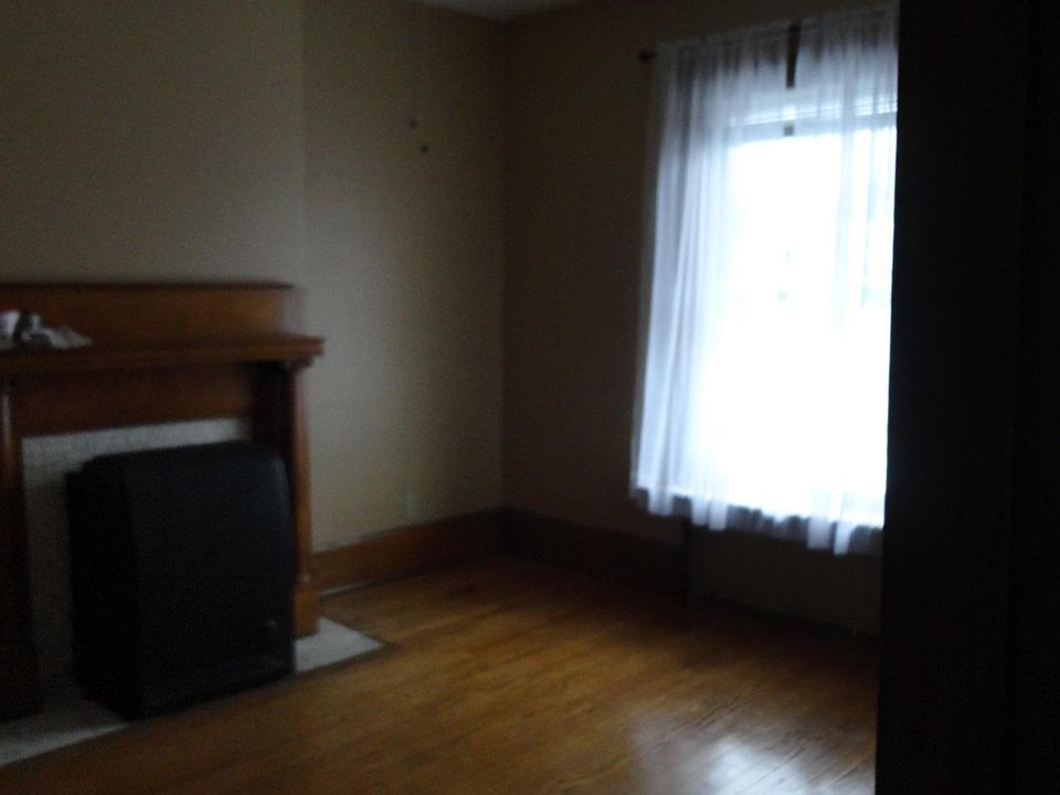 Living Room with hardwood floors, fireplace mantel, two large double-paned windows, large closet for extra storage, ceiling fan, and gas thermostat controlled heater.