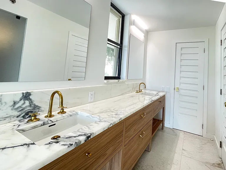 double vanity with marble counter tops and custom cabinetry complete the luxurious space