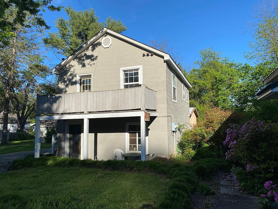 Front of house with full length porch and covered sitting area below. First story of the house is used by owners for storage.