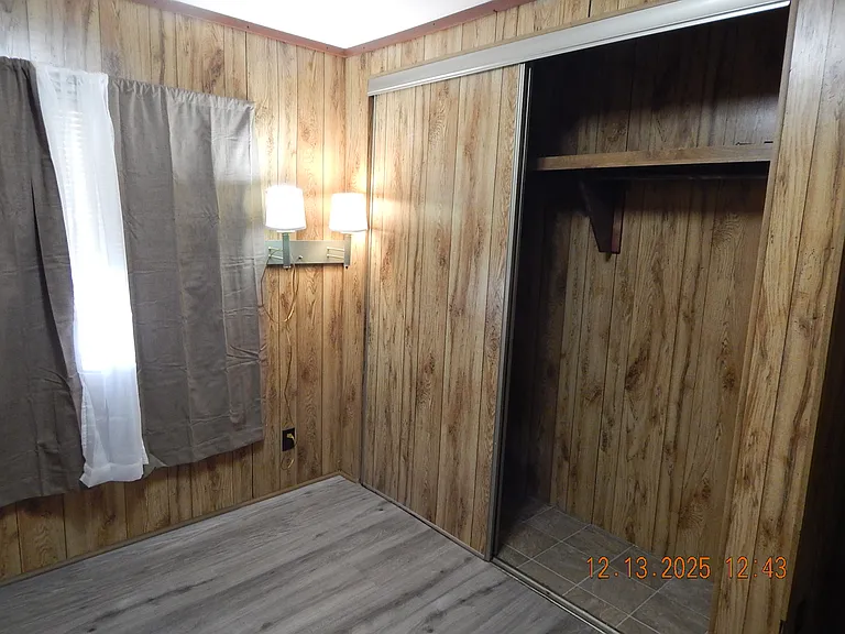 Master bedroom - closet entrance on right - curtains with drapes at rear window -- reading lamp next to window.