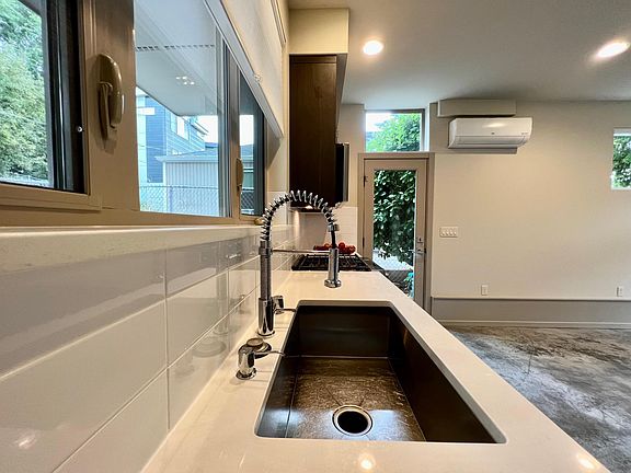 Quartz countertops and generous undermount sink. Note mini-split heat/ air conditioning, upper left.