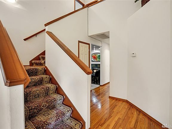 Entry with soaring ceiling and gleaming hardwood floors that extend through the hallway and into the kitchen.