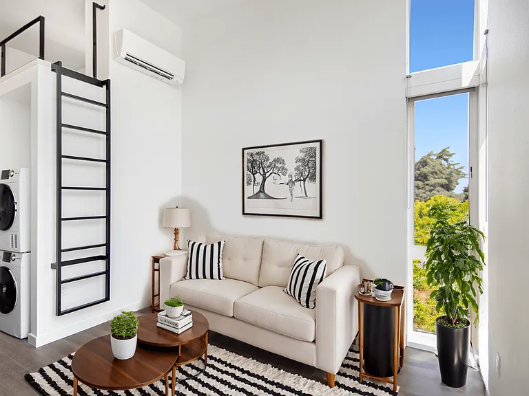 Relax in the cozy studio loft living room featuring a white couch and rug at Alt Capitol Hill.