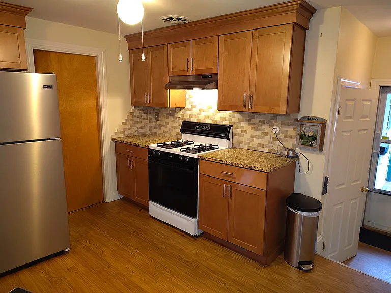 Kitchen showing gas stove, wooden cabinets, stainless steel refrigerator, ceiling fan.