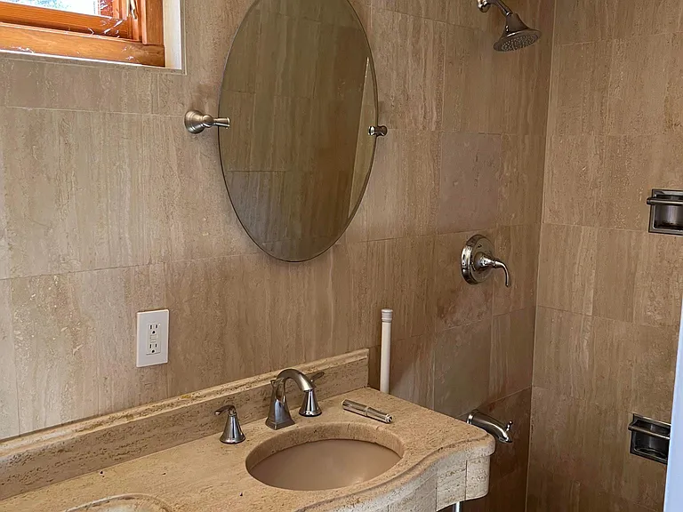 Lower-level bathroom with custom travertine sink, shower and tub