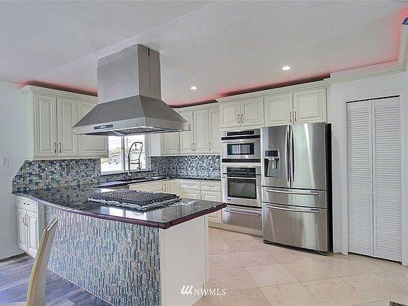 Custom designed 3CM Titanium granite counters in kitchen with tile flooring. Kitchen is open to dining room and living room.