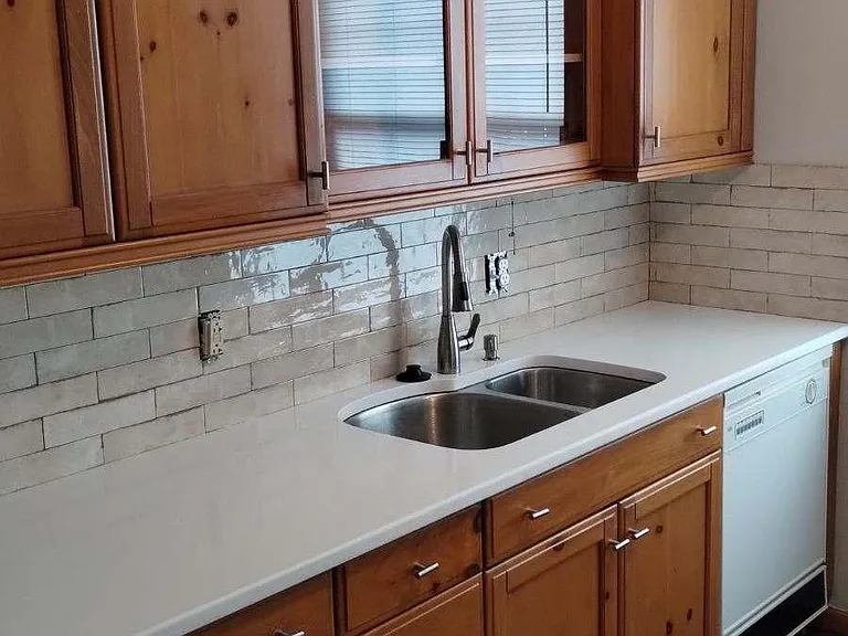 Kitchen with birch cabinets, stainless steel double-sink quartz counter top and porcelain backsplash. Stove, microwave, refrigerator and dishwasher included.