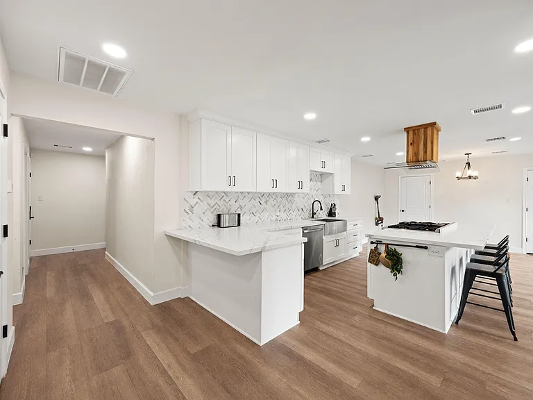 Open kitchen with oversized island, ample cabinet storage, and stainless appliances, flowing into the dining area.