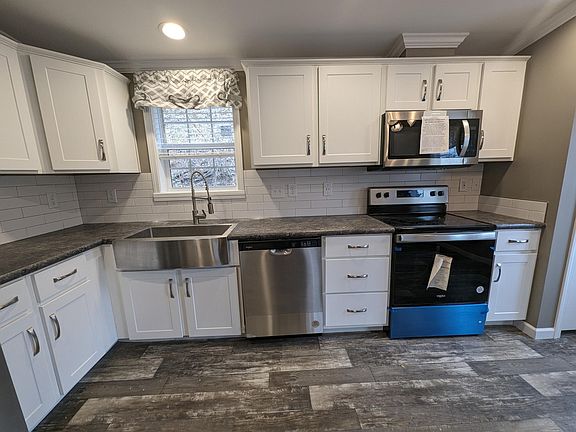 Farmers sink with window and light above, dishwasher, electric stove and microwave with exhaust fan