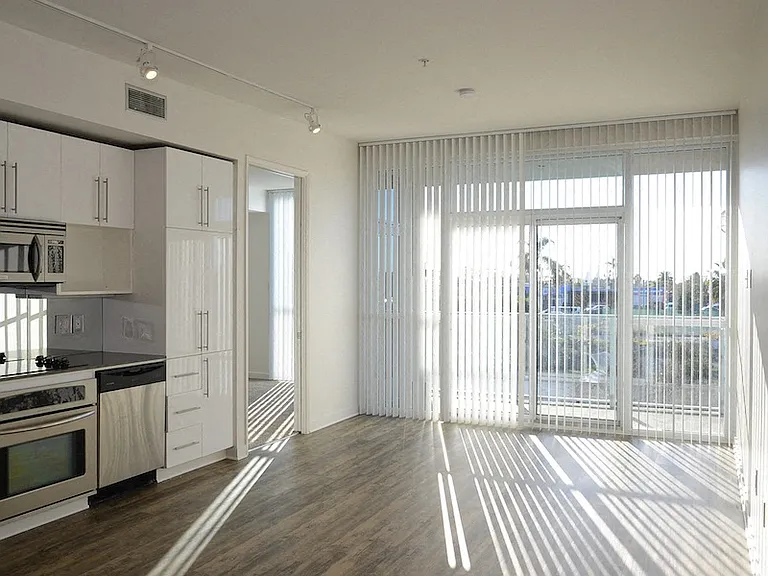 Open living space and door to carpeted bedroom at 12th Street Lofts in National City, California.