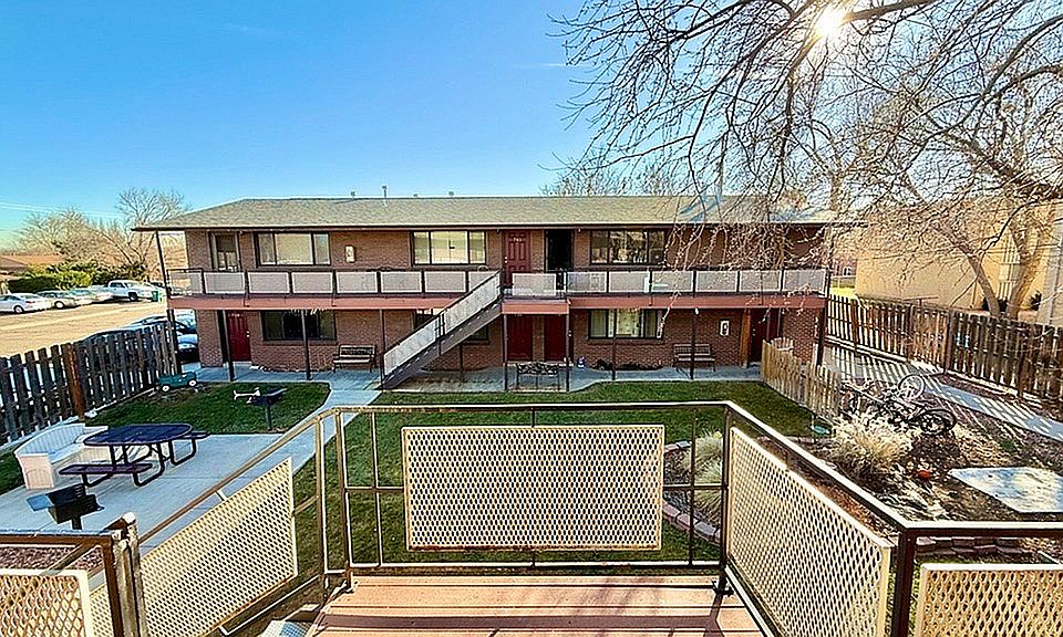 Inviting apartment building with sunlit courtyard, outdoor seating, and a charming landscape view.