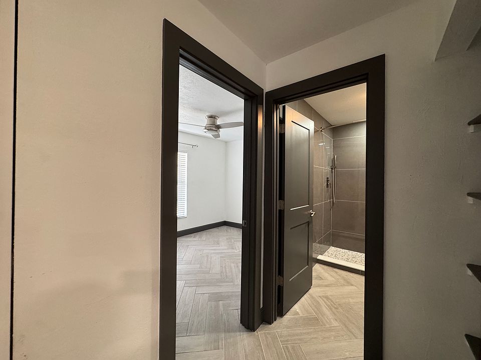 Rear bedroom with ceiling fan and glimpse into bathroom