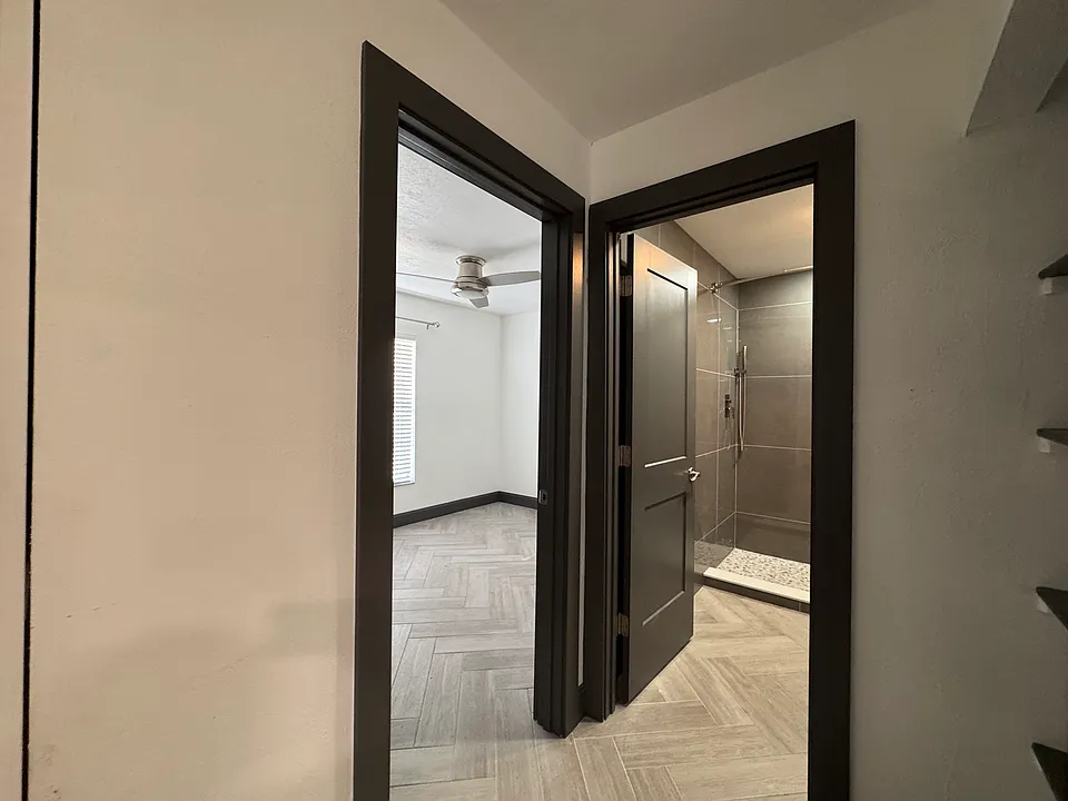 Rear bedroom with ceiling fan and glimpse into bathroom