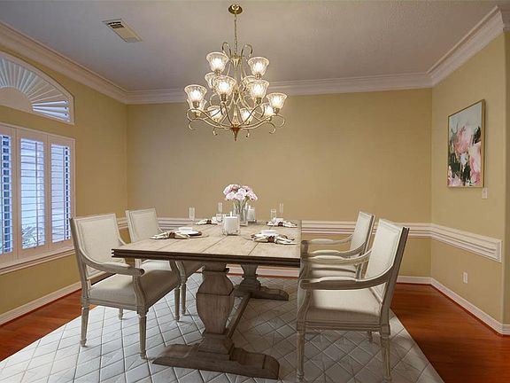 The formal dining room has chair railing, plantation shutters and a chandelier that makes this room shine. This photo has been digitally enhanced to show room layout.
