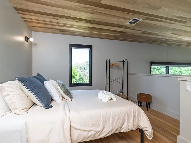 Bedroom 2 is lofted with a queen bed with open closet in the corner.