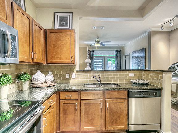 Kitchen with granite counter tops, stainless steel appliances, brown cabinetry.