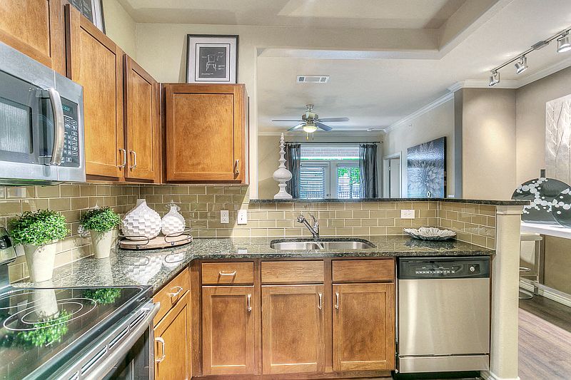 Kitchen with granite counter tops, stainless steel appliances, brown cabinetry.