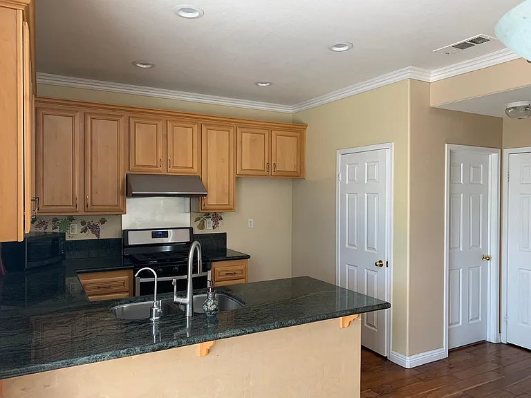 Kitchen with stainless steel vent hood and appliances.