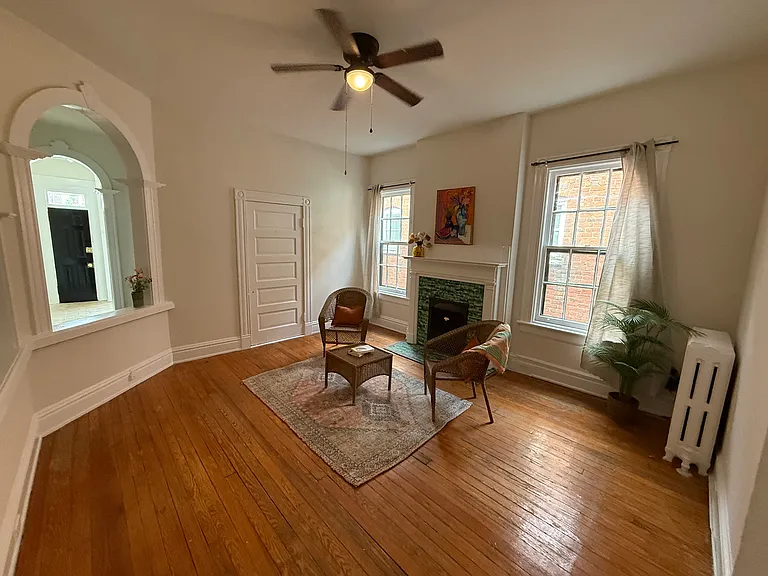 Spacious living room with decorative fireplace, fresh paint, ceiling fan and elegant archways and millwork.