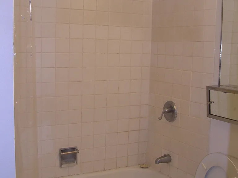 Bathroom has a very large well-lit mirror above toilet and sink.