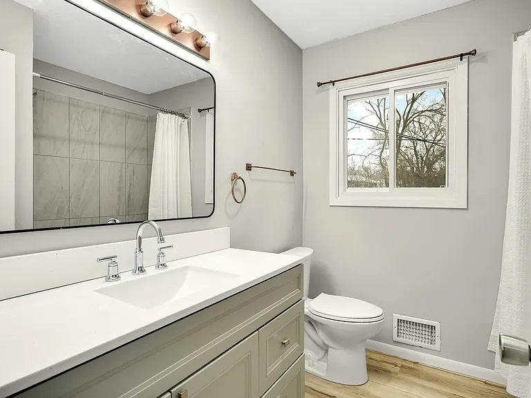 Bright upper-level full bath featuring new vanity, updated lighting, new flooring, and ceramic tile shower surround