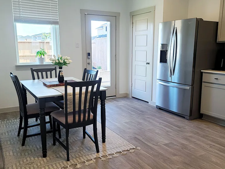 Eat-in kitchen area with a four-seat dining table, stainless-steel appliances, and a door leading to the backyard.