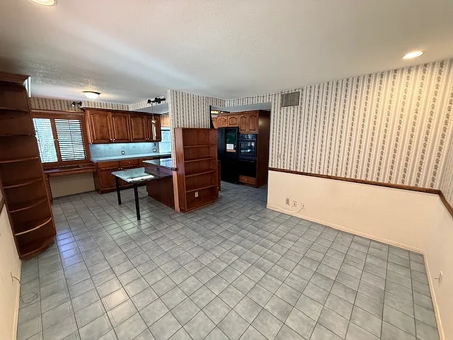 View of the kitchen from the den. There is a built in desk in the kitchen in front of the window.