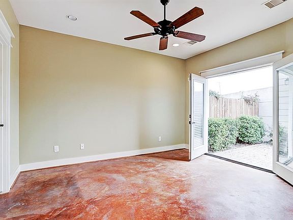 The master bedroom has stained concrete flooring, high ceiling, ceiling fan, neutral paint scheme and french door access to the patio in the rear of the home.