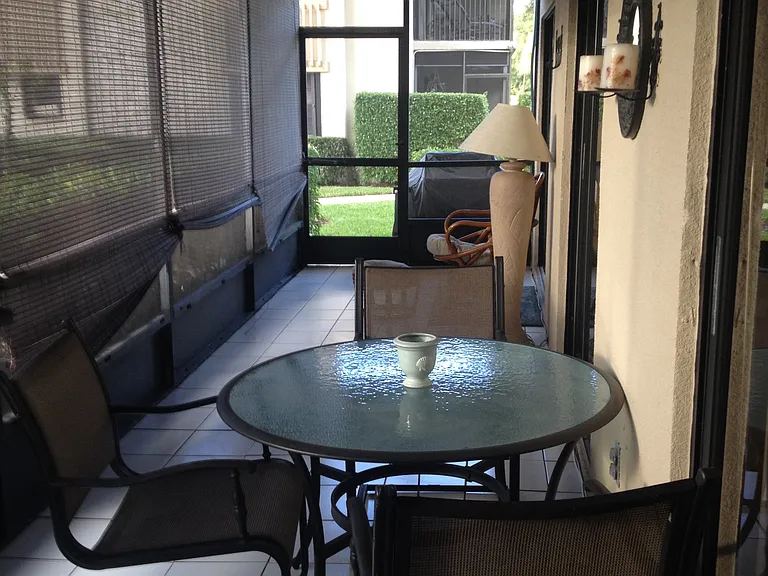 large screened patio with table and chairs and two loungers.