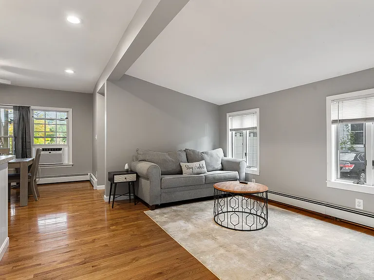 Open floor plan, hardwood flooring, neutral paint, recessed lighting, window blinds, baseboard heating, window AC unit.
