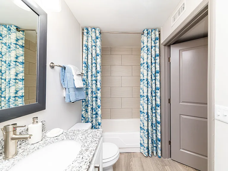 Bright bathroom with granite counters and bathtub