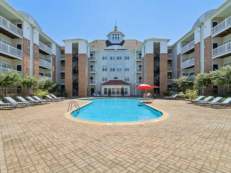 Serene swimming pool with lounge seating, patio tables, and umbrellas