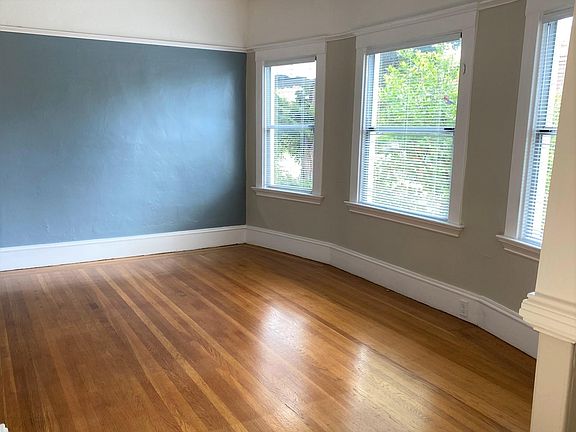 Living room features an accent wall, beautiful red oak hardwood, and charming original woodwork.