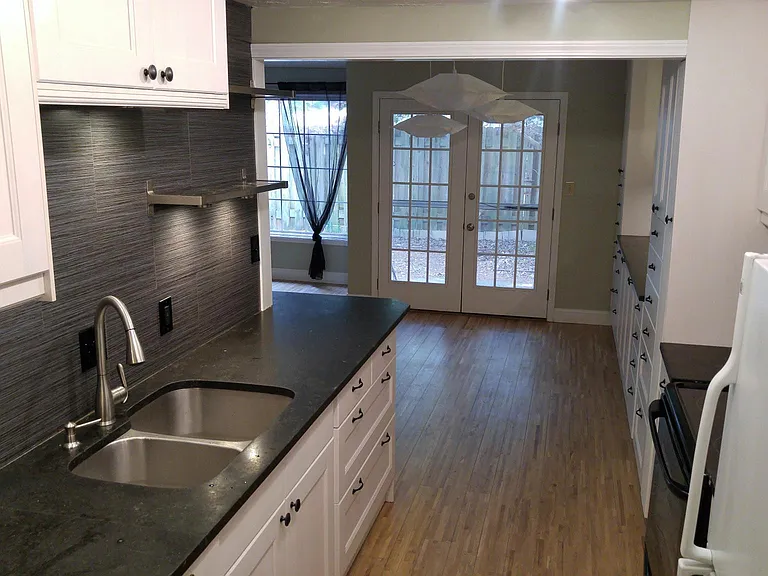 Double galley kitchen view through living area into back patio.