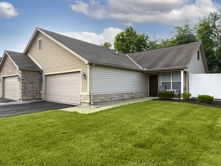 Welcome to a beautifully designed home featuring a classic grey roof and a crisp white fence, creating inviting curb appeal.