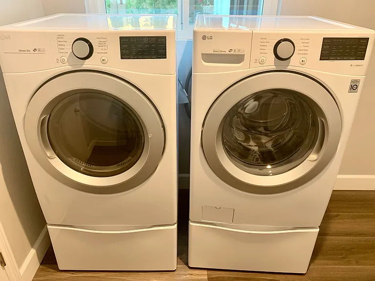 Dedicated laundry room with modern LG high efficiency washer and dryer on stands for easy loading and unloading
