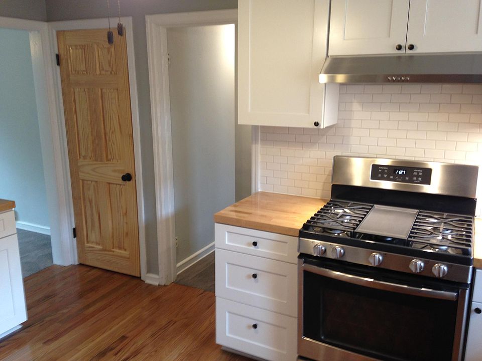 Stainless steel gas range and hood with preparation space on both sides.