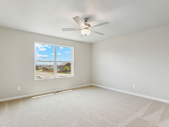 The master bedroom has a ceiling fan and large window.