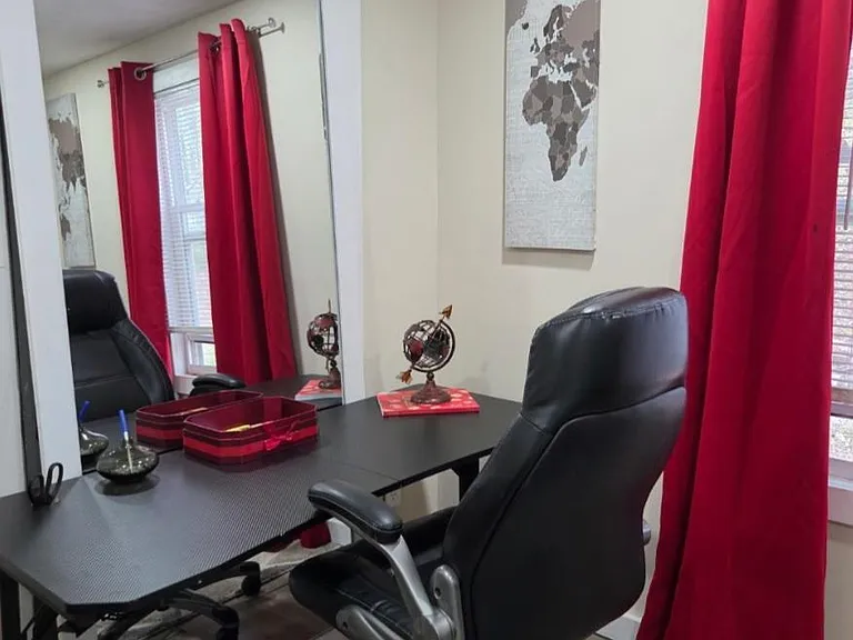Dedicated work area with a desk and chair, plus a window with curtains for privacy and natural light.