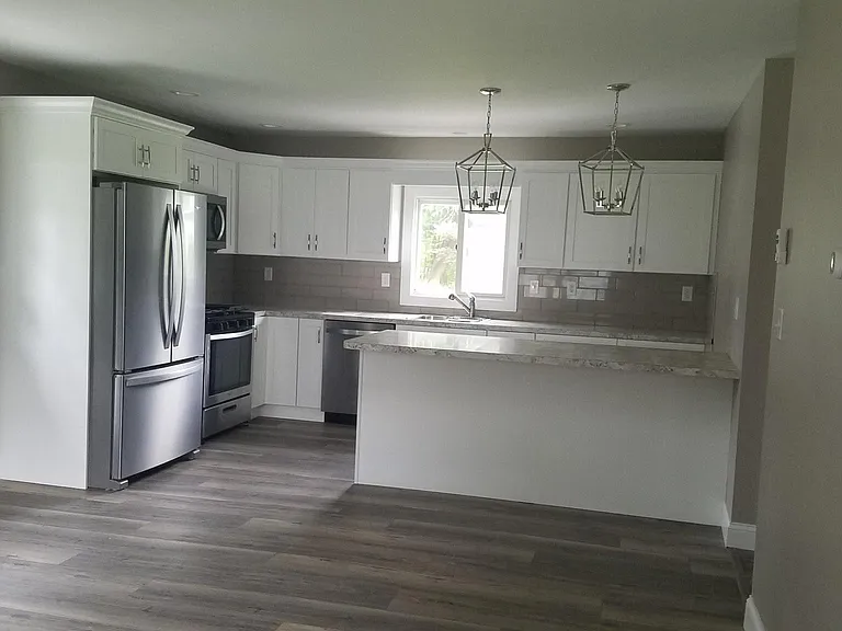 Large kitchen with peninsula and new cabinets and appliances , tile back-splash