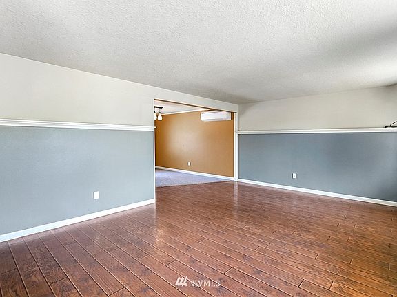 Living room with laminate flooring is adjacent to dining room with one of 3 ductless heat pumps