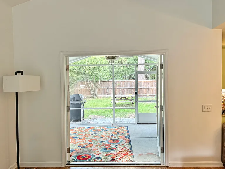 Living room leads to French door screened in porch
