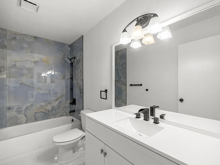 View of the primary bathroom with brand new tub, shower tile, vanity, and faucets