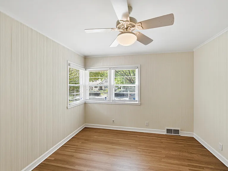 One of the additional bedrooms with newly stained wood floor and corner windows. Also used as office with view of front garden.