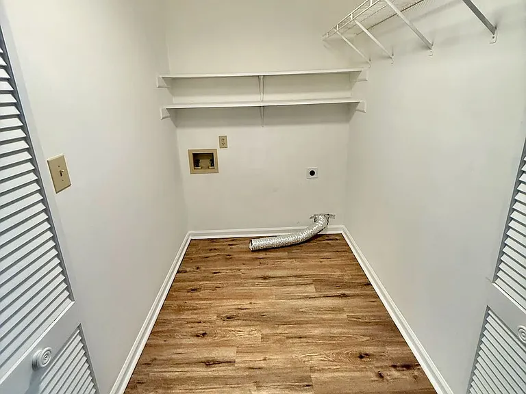 Efficient hall laundry_ dedicated closet with washer/dryer hookups and built-in shelving keeps chores organized - vinyl plank floors resist spills for easy cleanup, so laundry day stays quick and tidy.