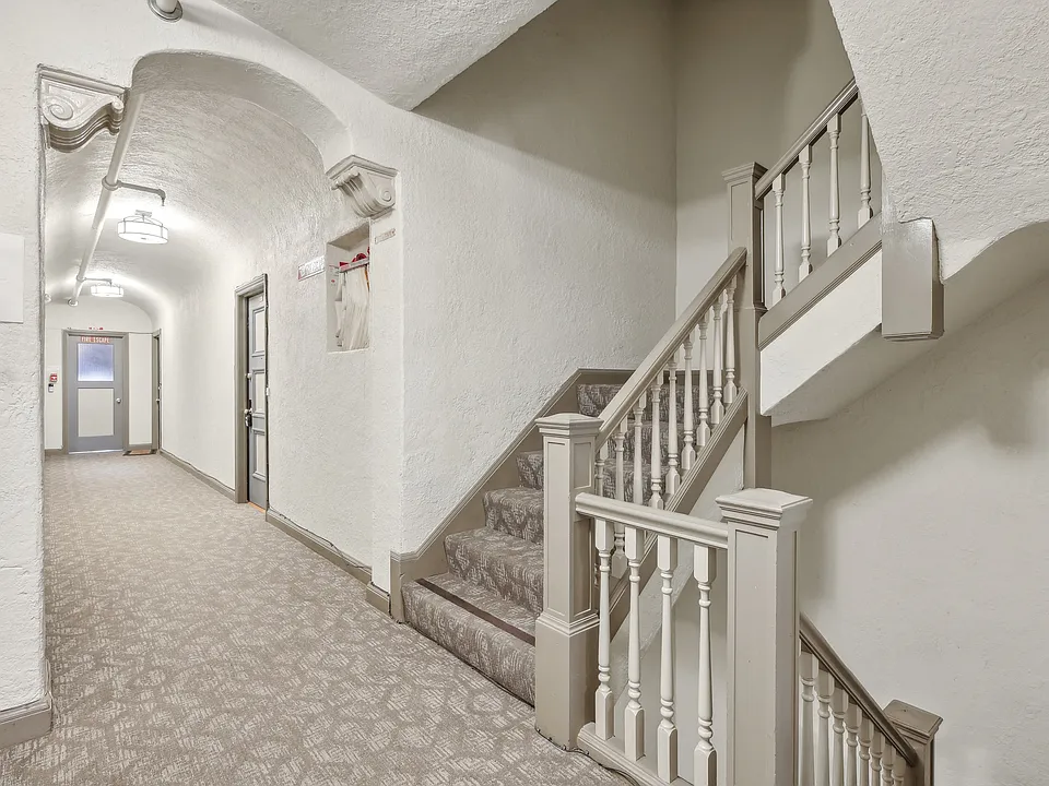 Hallway with a carpet, set of stairs with a railing and banister