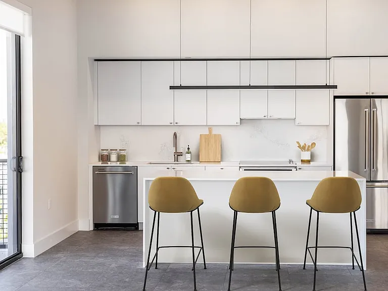 Signature Collection kitchen with white cabinetry, white marbled quartz countertop and backsplash, wine fridge, and upgraded stainless steel appliances